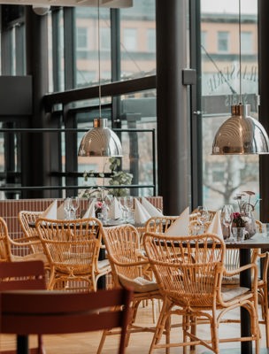 Restaurang med uppdukade bord och korgstolar