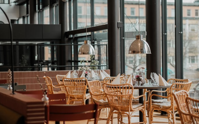 Restaurang med uppdukade bord och korgstolar