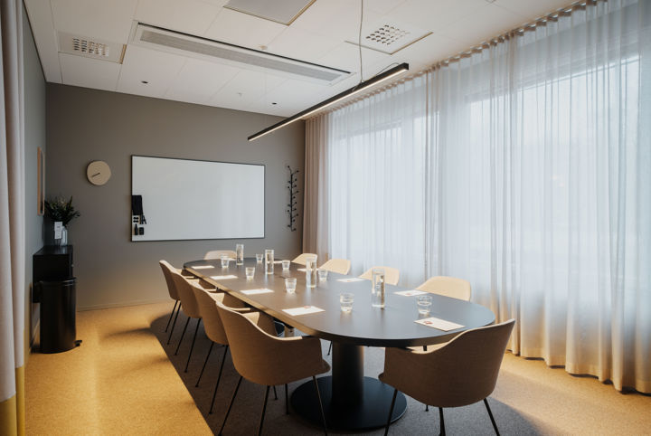 Konferensrum med stora fönster, möblerad i styrelsesittning