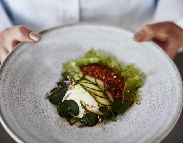 En servitör håller i en tallrik med en maträtt