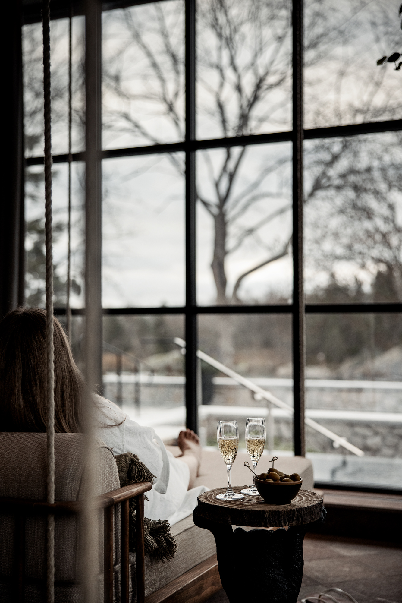En person njuter i spats relaxavdelning, på bordet bredvid står två glas champagne och snacks
