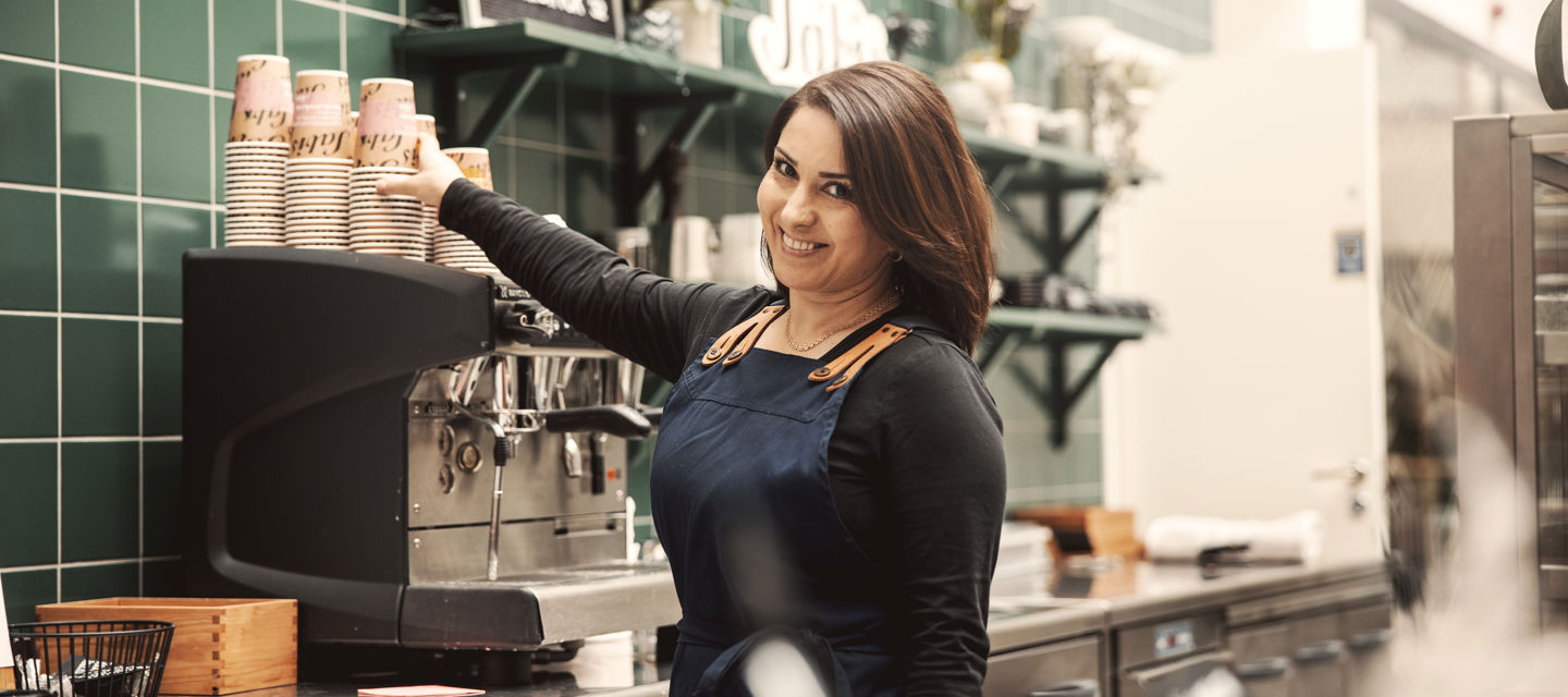 En barista ska göra kaffe och ler in i kameran