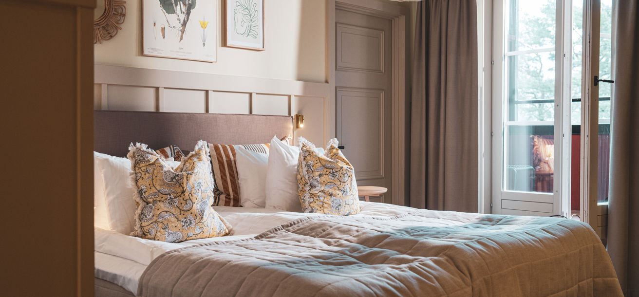 Bäddad hotellsäng i ett rum med tillhörande balkong