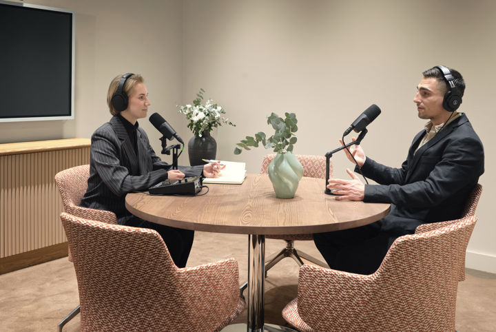 Två personer spelar in en podd i ett litet mötesrum