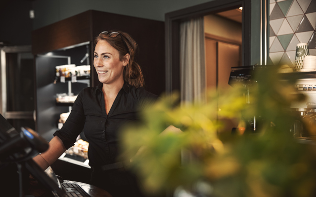 Medarbetare ler bakom kassan