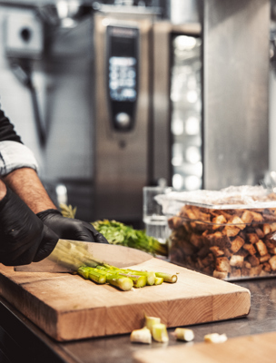 Kock hackar sparris på en skärbräda
