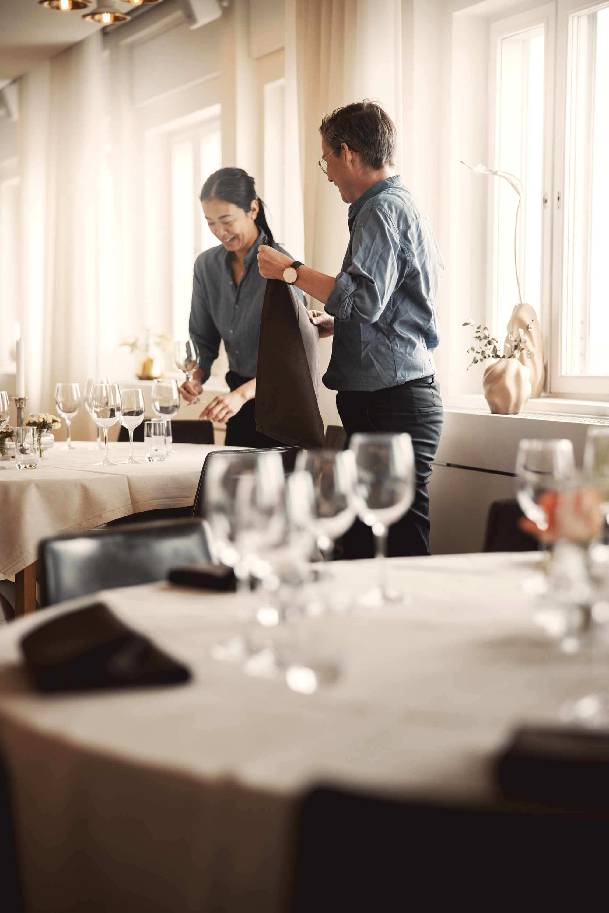 Två anställda dukar bord inför fest