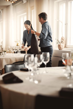 Två anställda dukar bord inför fest