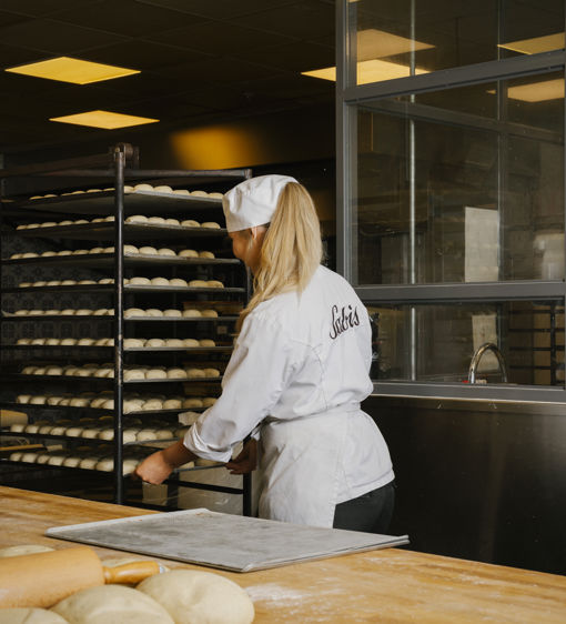 Kvinnlig bagare plockar med plåtar