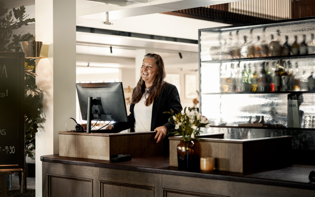 Receptionister står vid disken och är redo att välkomna gästerna