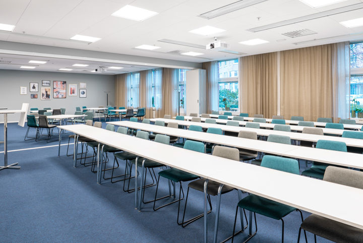 Stor konferenslokal som är inrett i blåa toner och möblerad i skolsittning