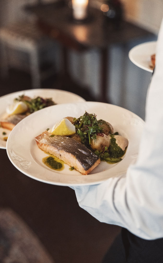 Servitör serverar lax och potatis