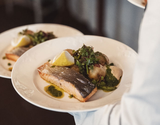 Servitör serverar lax och potatis