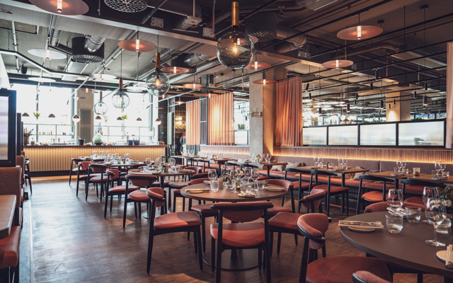 Stor och rymlig restaurang med runda bord och mjuka stolar