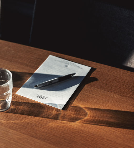 Ett anteckningsblock och penna ligger på ett träbord