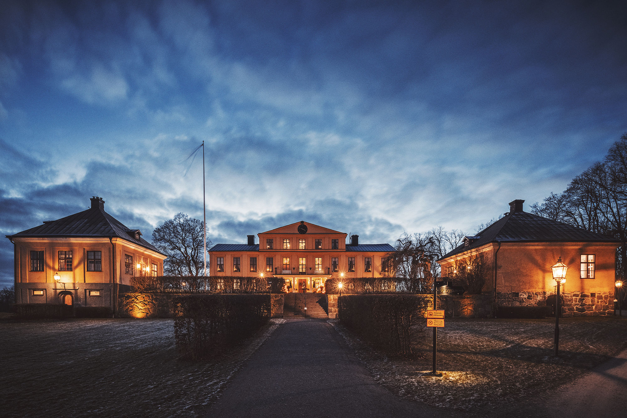 Herrgårdens fasad upplyst av lampor en höstkväll