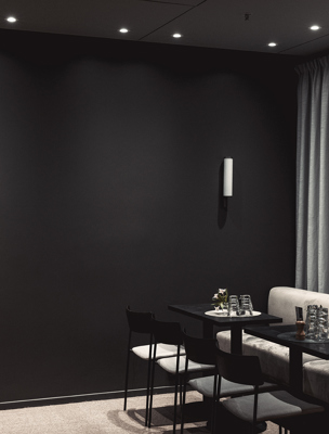 Mindre bord och vägghängd soffa i ett rum i mörka färger