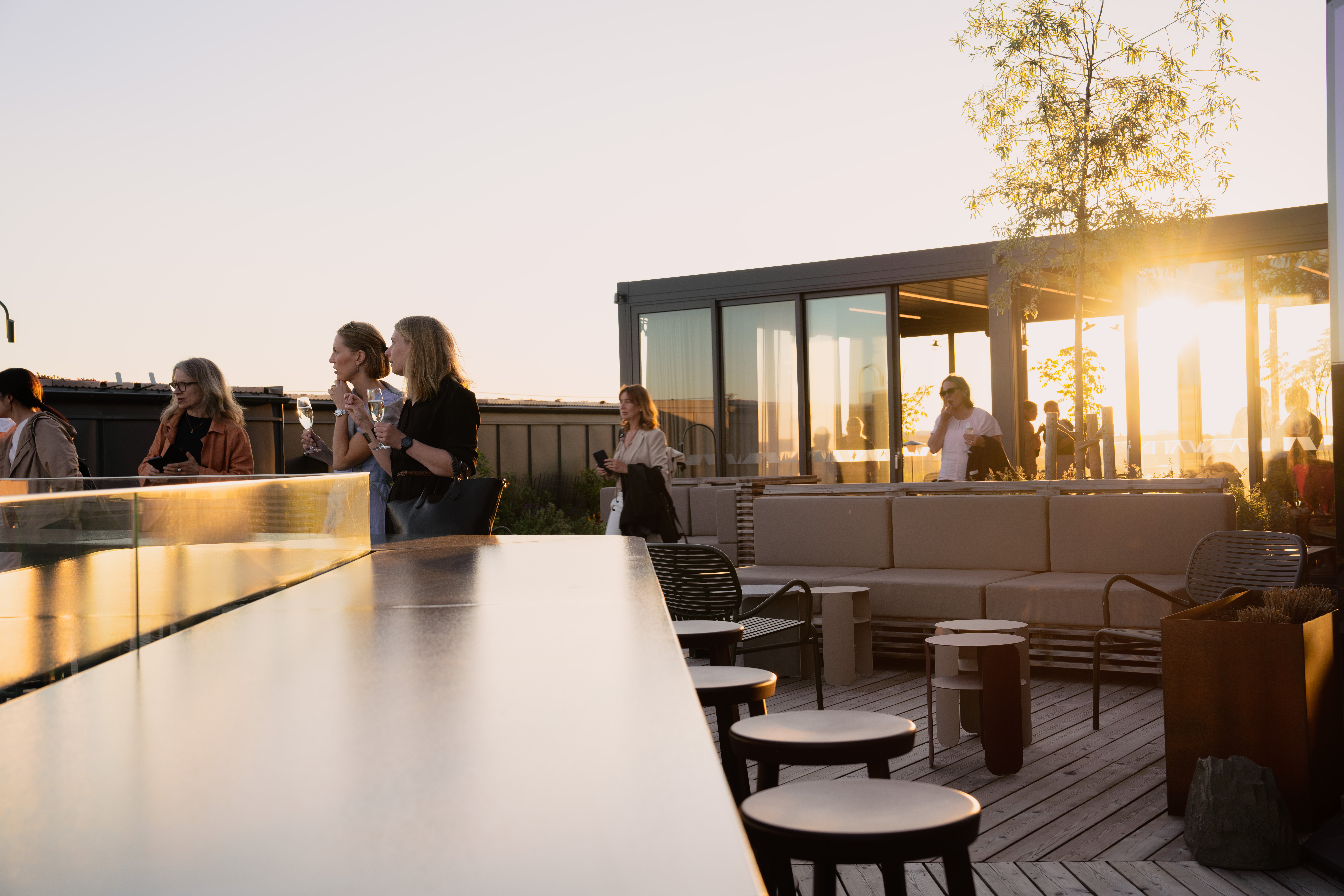 Människor minglar på takbar med terrass och inomhusytor