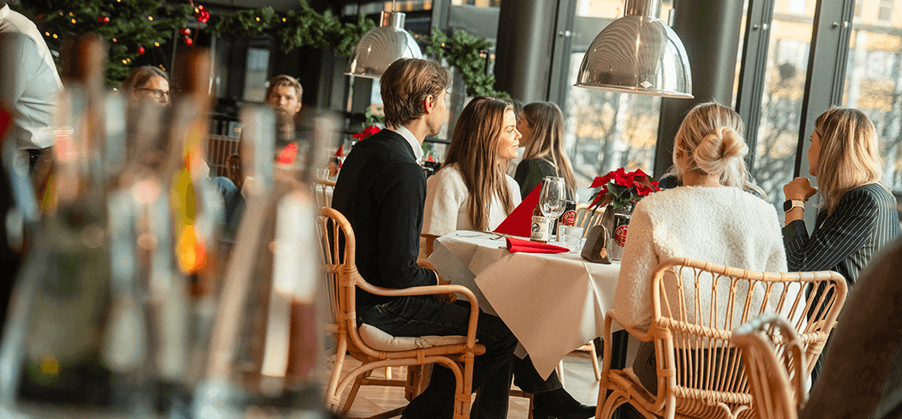 Människor sitter vid runda bord och äter julbord