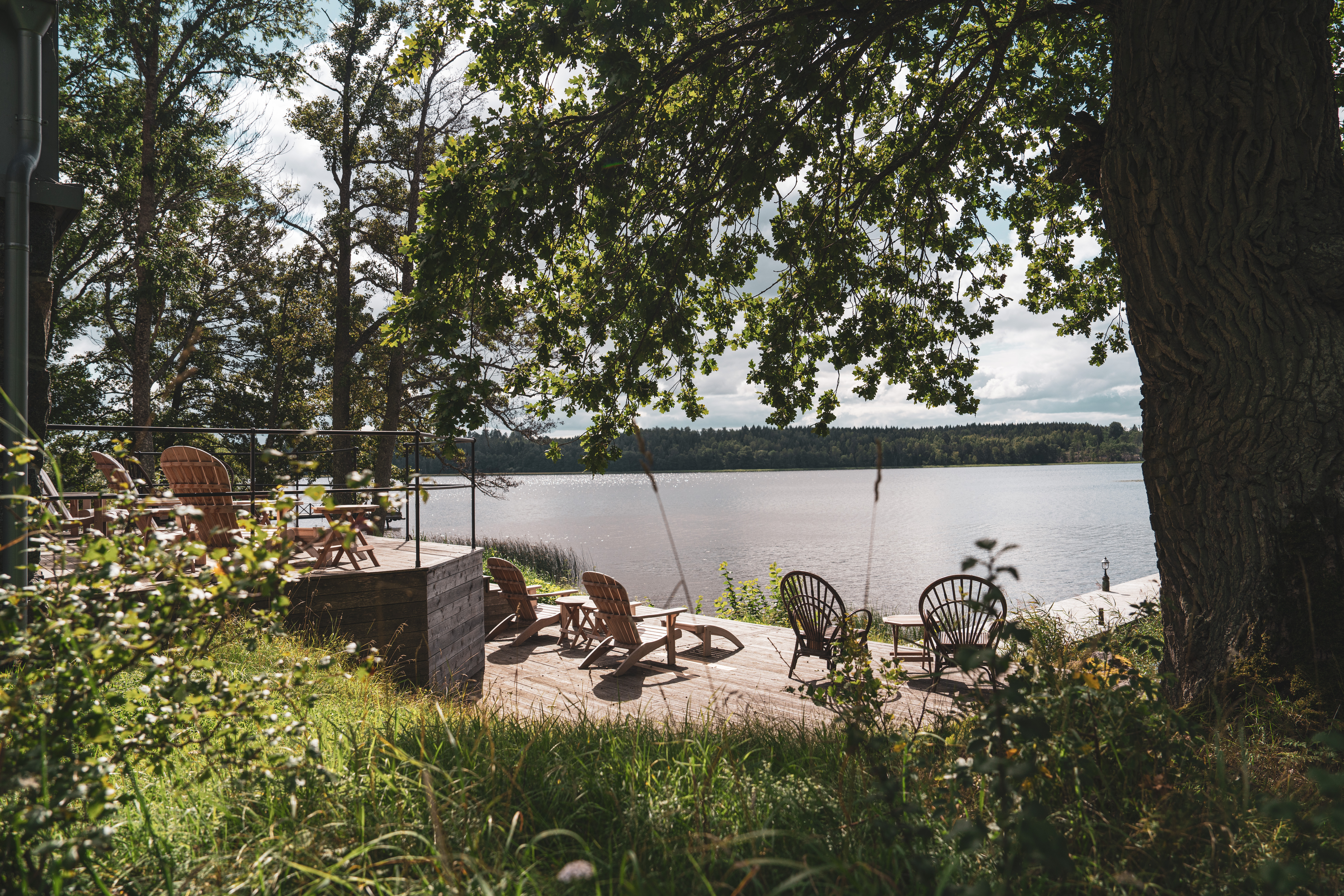 Uteplats med solstolar framför bastun som ligger vid vattnet