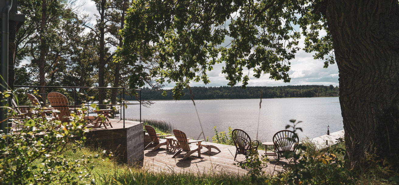 Uteplats med solstolar framför bastun som ligger vid vattnet
