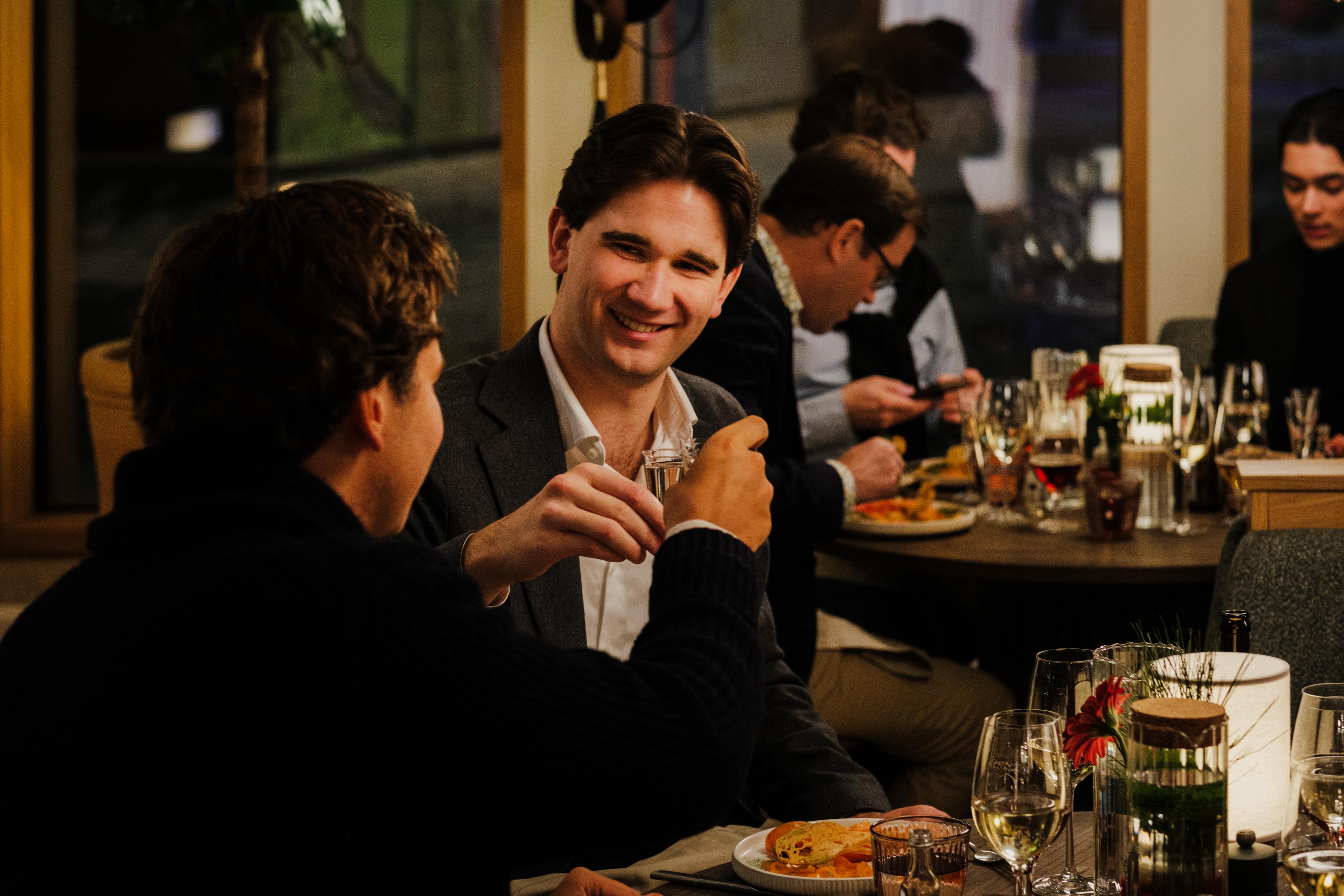 Två män dricker nubbe och skålar vid ett julbord