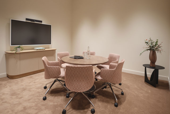 Litet konferensrum med ett runt bord och sköna ljusrosa fåtöljer