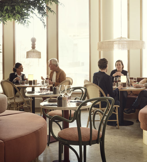 Gäster sitter i en restaurang som är inredd i ljusa rosa toner