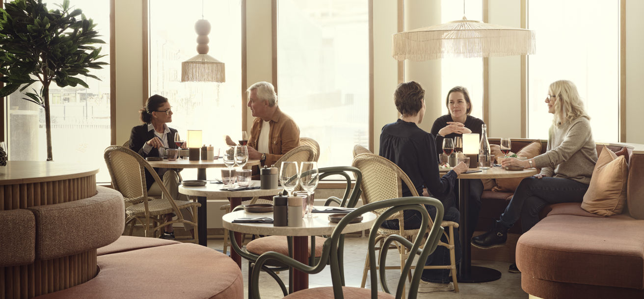 Gäster sitter i en restaurang som är inredd i ljusa rosa toner